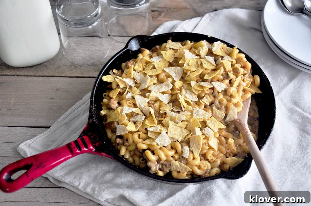 Beefy Taco Mac and Cheese simmering in a vibrant red cast iron skillet.