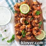 Four blackened shrimp skewers on a wood cutting board with cilantro sprinkled on top.