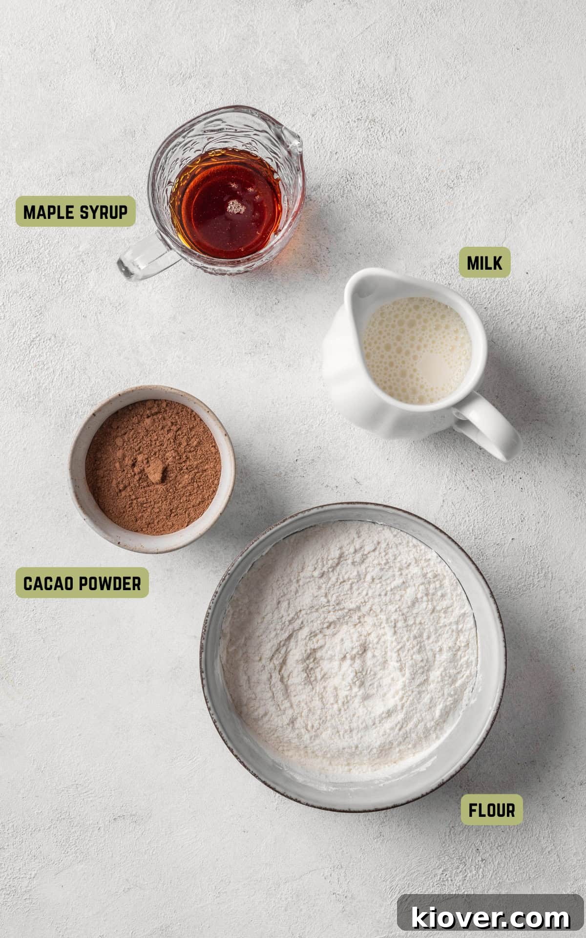 Decadent Chocolate Pancakes 3 Individual ingredients for chocolate pancakes including self-rising flour, cacao powder, milk, and maple syrup.