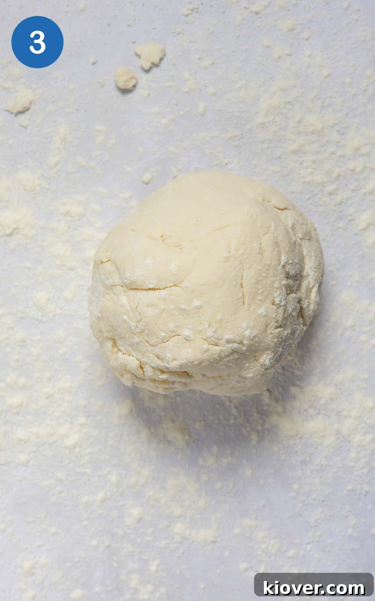 The prepared naan dough, rolled into a smooth, compact ball, resting on a lightly floured work surface.