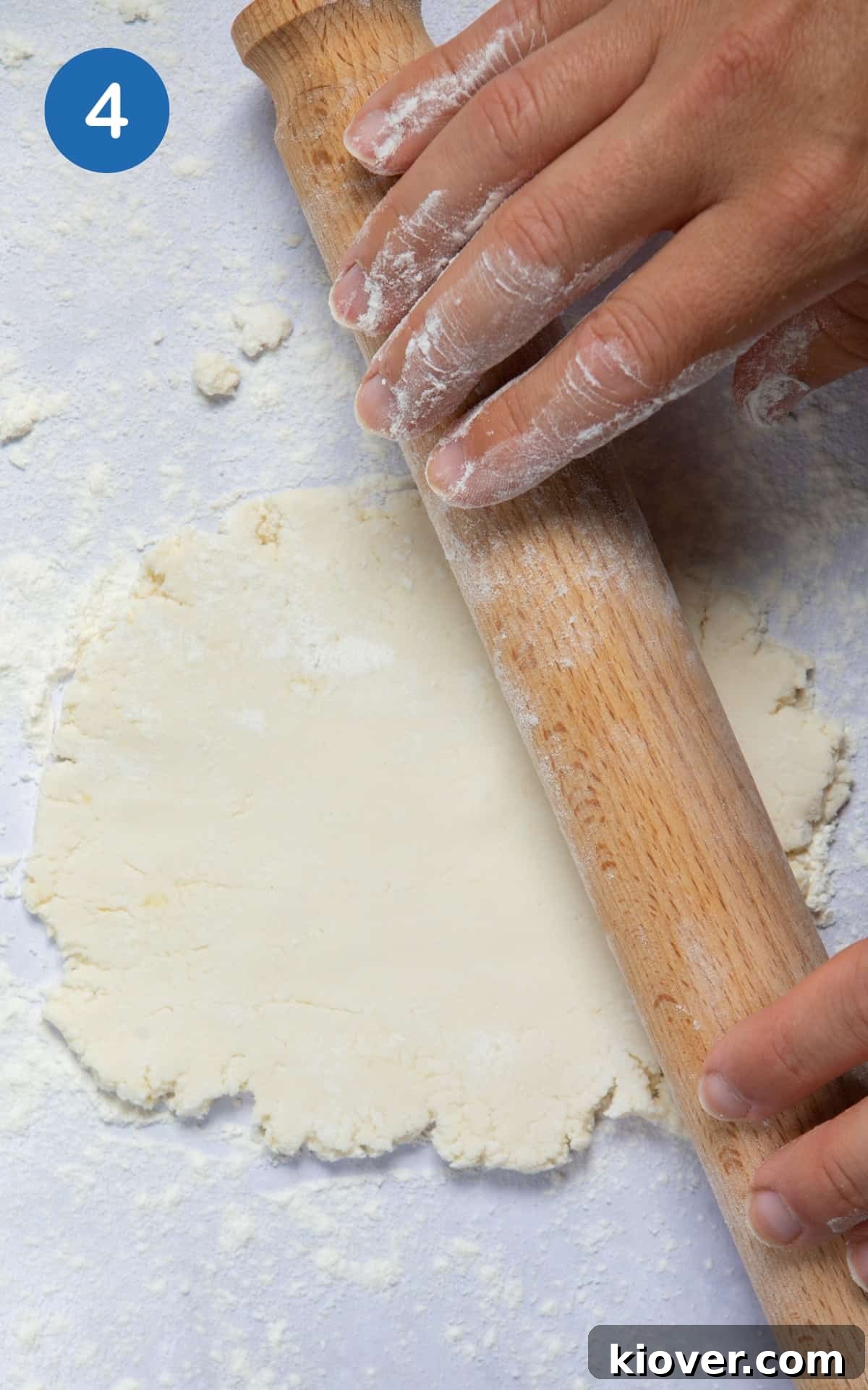 Naan dough being skillfully rolled out with a rolling pin on a floured surface, creating a flat, even shape.