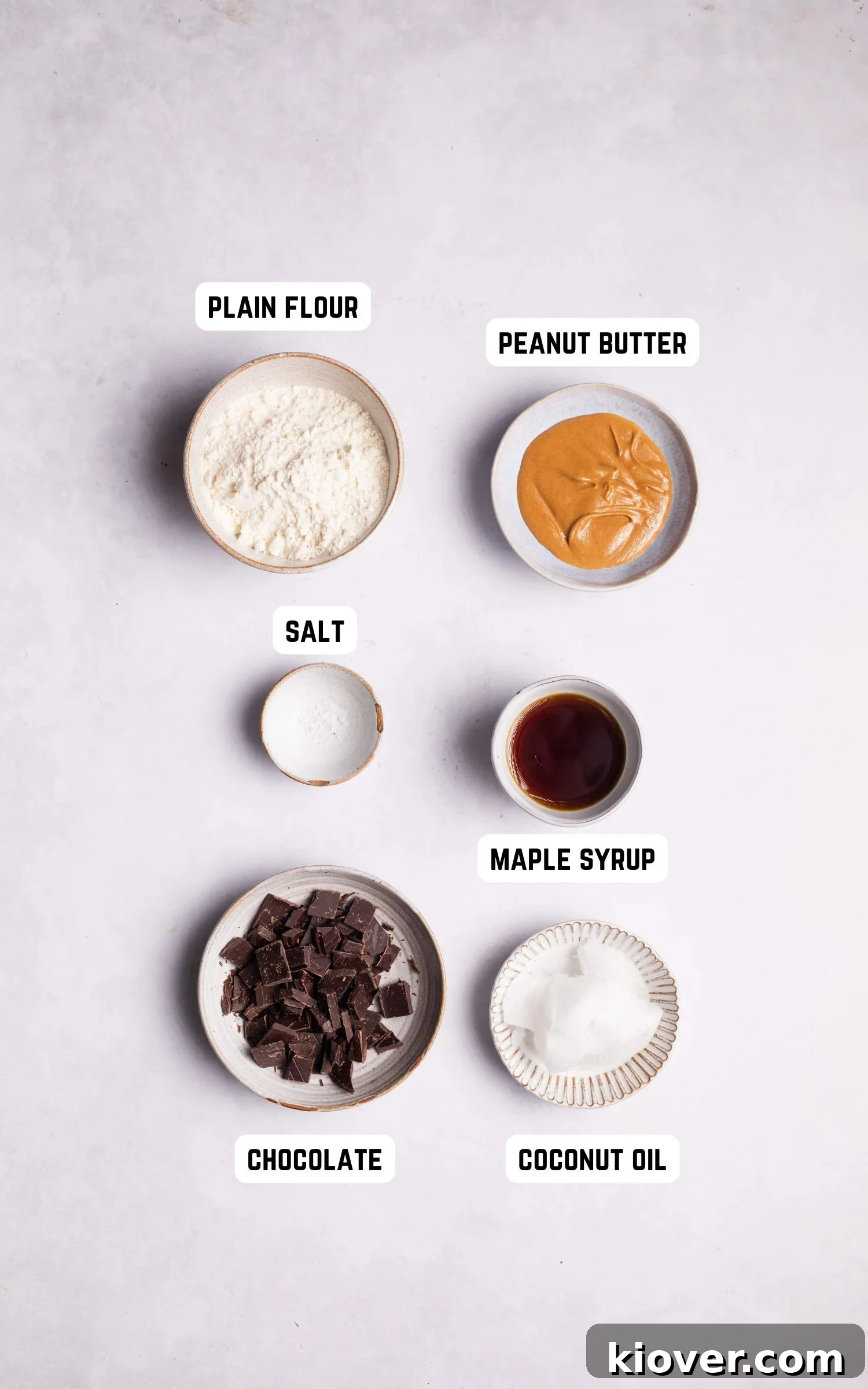 A flat lay photograph of the ingredients required to make Vegan Peanut Butter Cookies, including coconut oil, maple syrup, peanut butter, flour, salt, and chocolate chips.