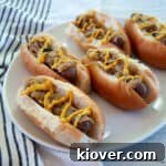 Five brats in buns and topped with onions and mustard.