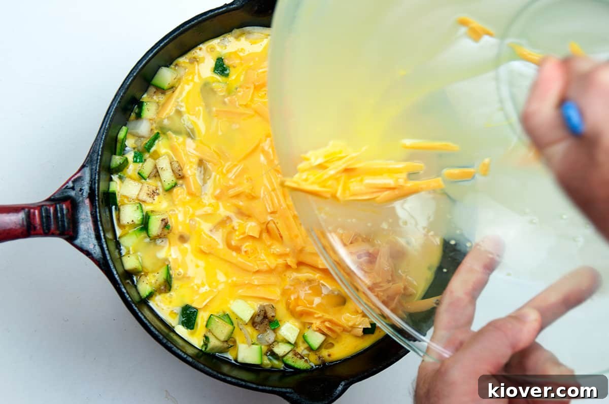 The rich egg and cheese mixture is carefully poured into a hot cast iron skillet, joining the sautéed vegetables to begin forming the frittata.
