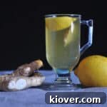 Hot toddy for a cold pictured with a lemon and ginger on a tablecloth covered counter