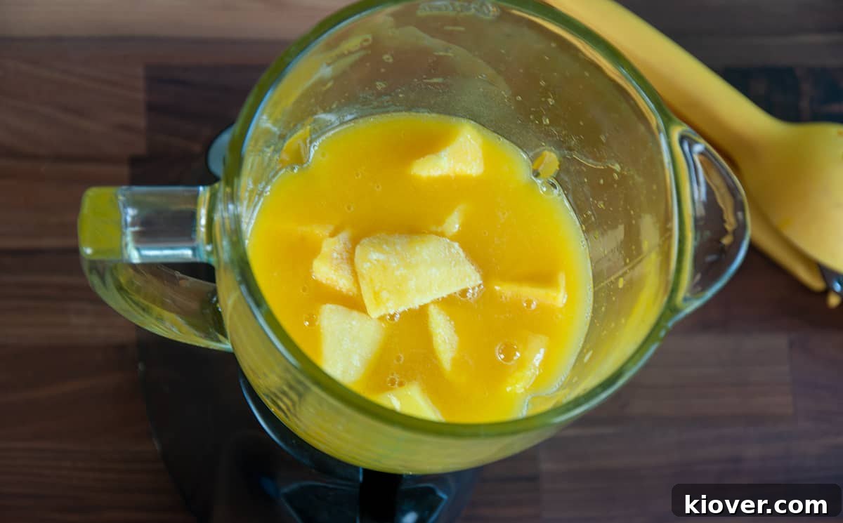Blender filled with frozen mango and juice.