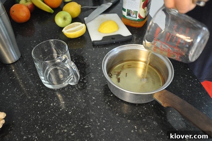 Getting Apple Ginger Hot toddy ingredients put together. Pouring cider into pot with fruit in background