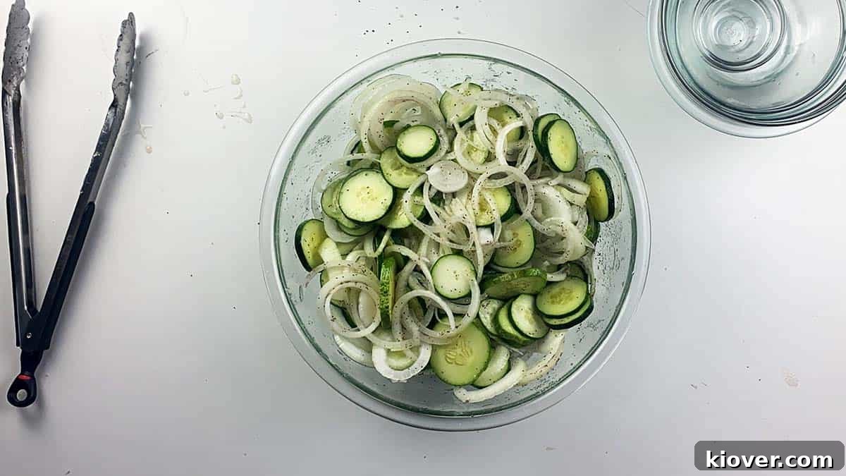 Effortless Fridge Pickles 2 Onions, cucumbers, sugar, vinegar, and celery seed in bowl.