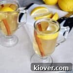 Best Hot Toddy recipe. Hot toddy on a table with lemon, cinnamon, and a cutting board.