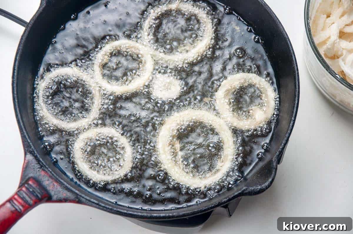 Hearty German Cheese Spaetzle 2 Onion rings frying in cast iron skillet.
