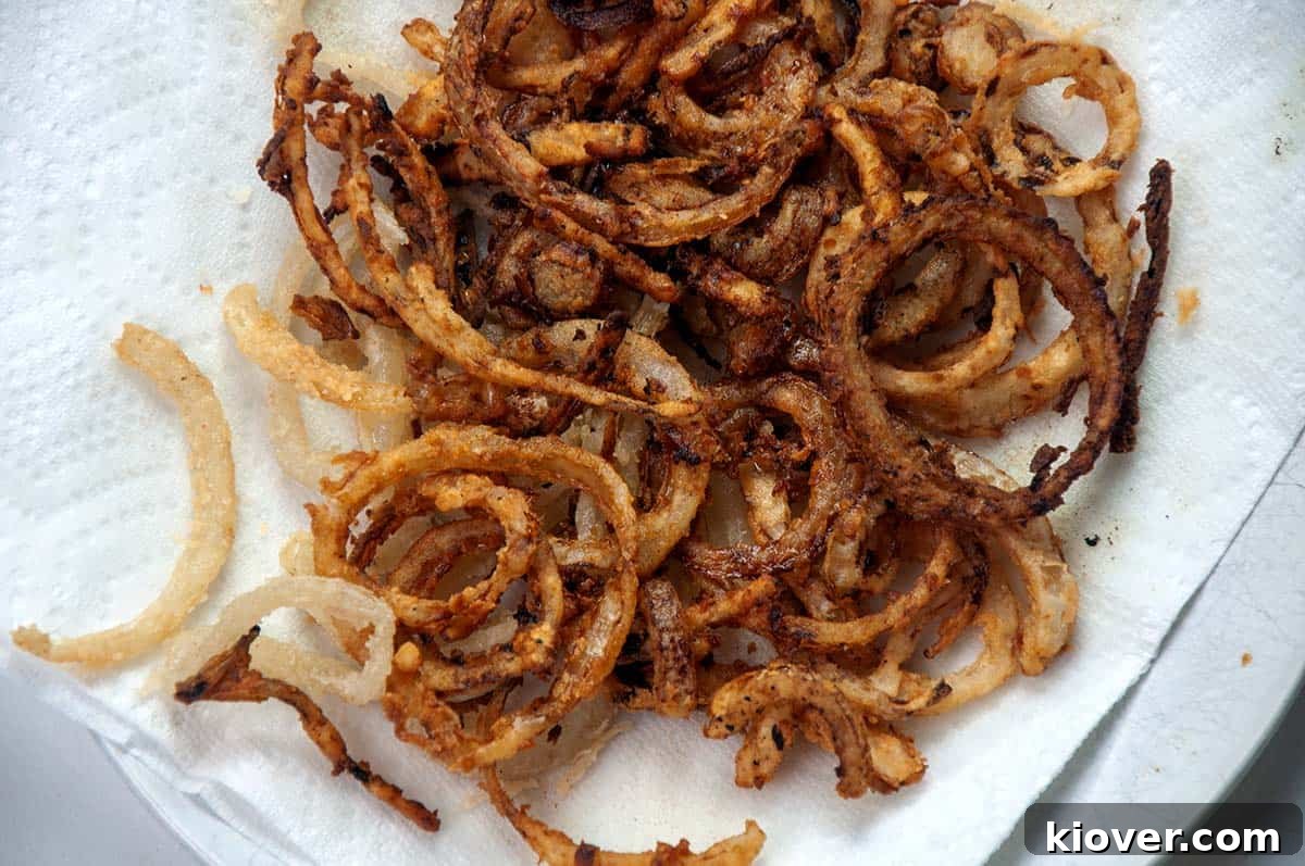 Hearty German Cheese Spaetzle 3 Fried onion on a paper towel-lined plate.