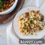 German Käsespätzle dumplings on a white plate with a casserole dish full of it to the side.