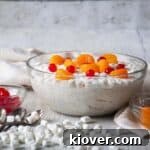Large bowl of frog-eye salad with marshmallows, cherries, and tangerine segments on the side.