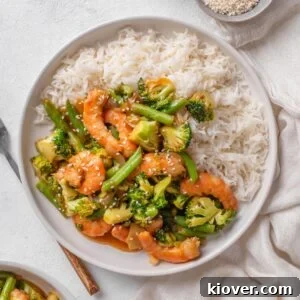 prawn stir fry served on a white plate with white rice.