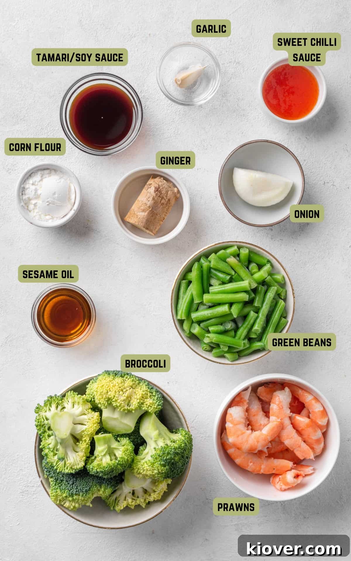 prawn stir fry ingredients laid out on a marble background, including fresh vegetables, oil, and sauces.