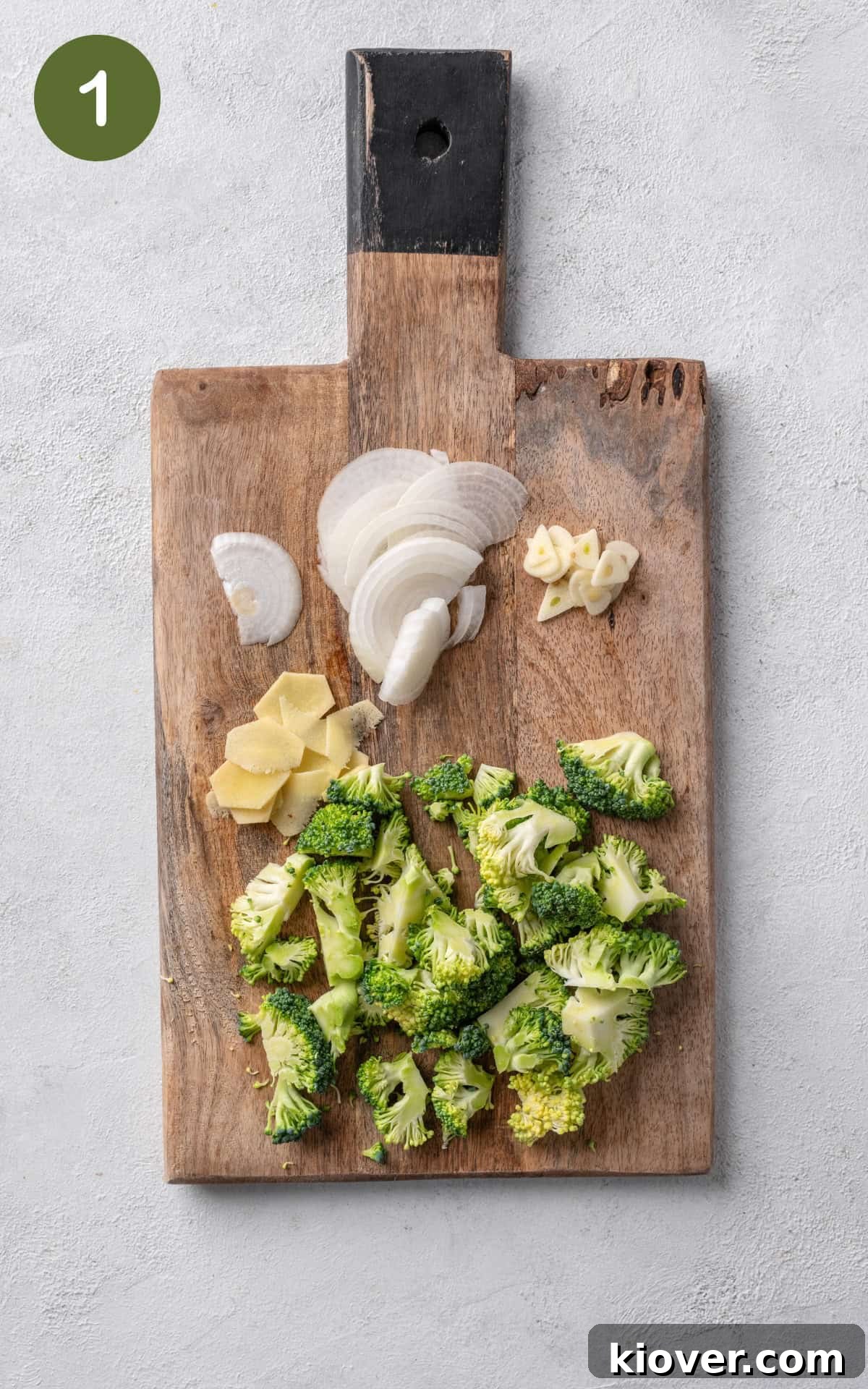 chopped broccoli, onion, ginger, garlic on a wooden chopping board, prepped for stir fry.