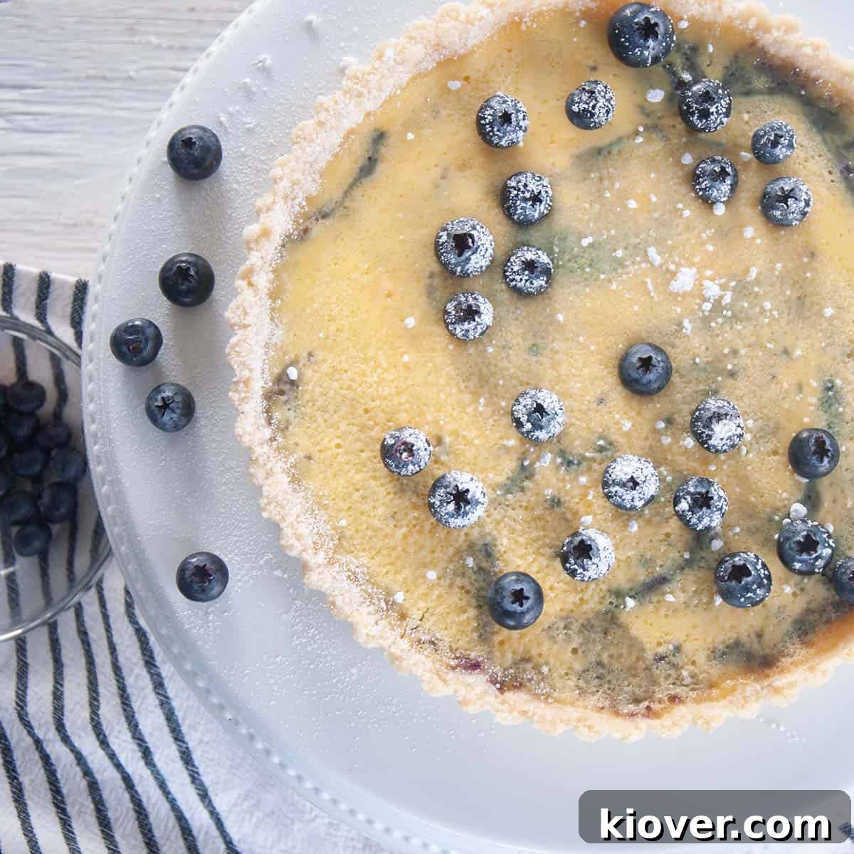 Blueberry Tart Whole blueberry tart with fresh blueberries on top and a on a white platter.