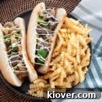 Two Bison Philly Cheesesteaks on a plate with fries.