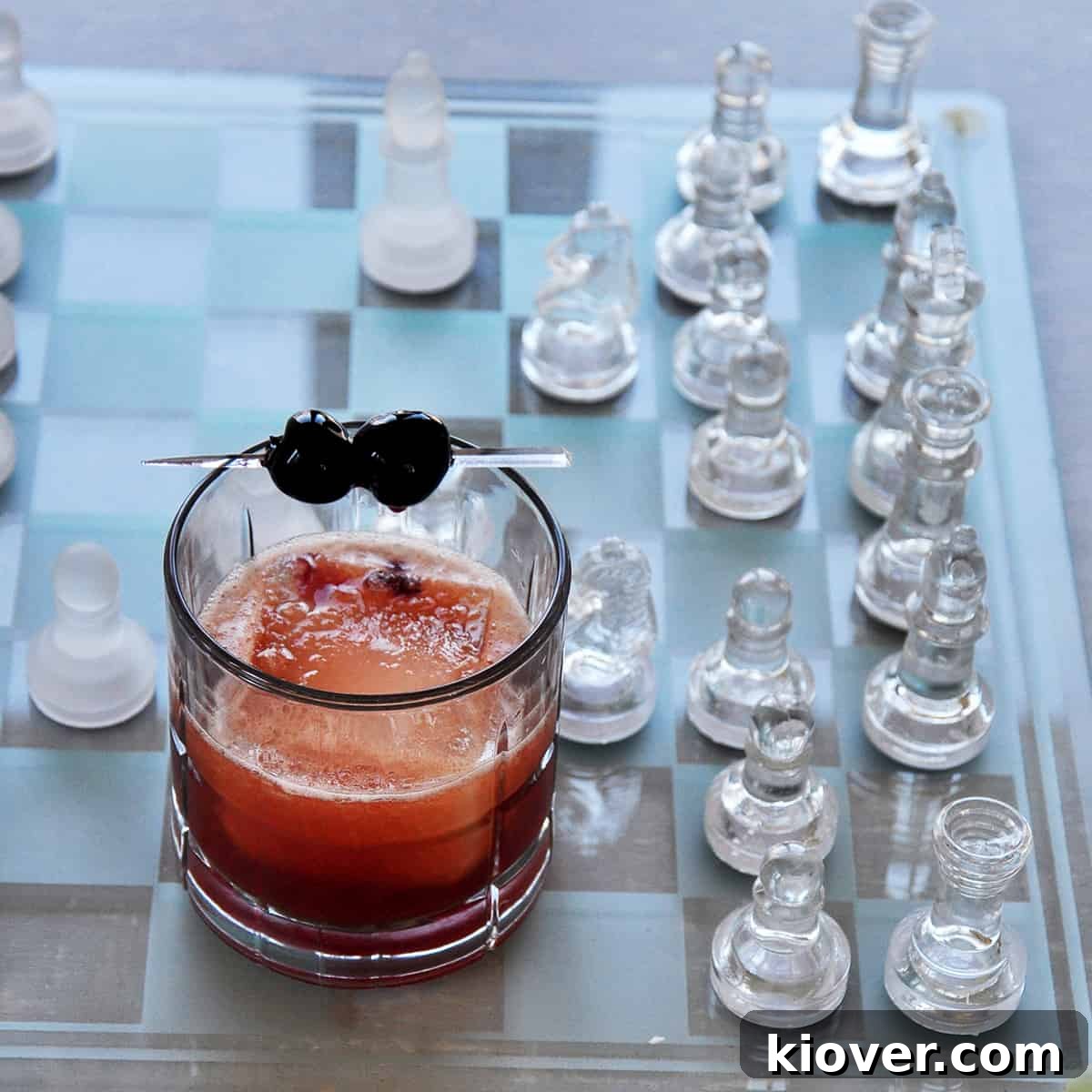A perfectly crafted Manhattan cocktail in a stylish lowball glass, adorned with a single large ice cube and two vibrant cherries, exuding classic elegance.