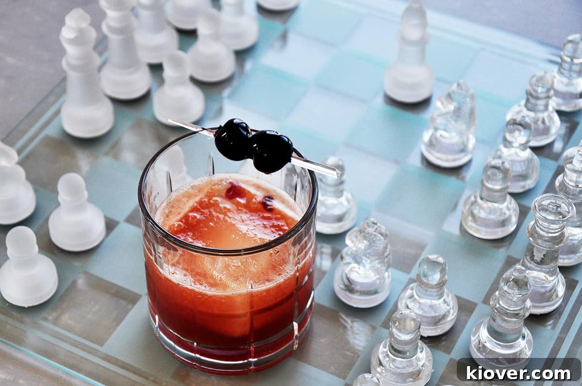 A stunning Manhattan cocktail, perfectly amber-hued, resting on a sophisticated glass chessboard, inviting a moment of thoughtful enjoyment.