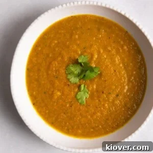 Carrot & Coriander Soup served in a white bowl with coriander on top.