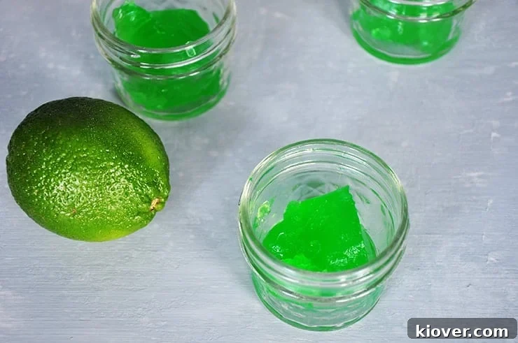 side view of two Jello shots in small mason jar with a lime.
