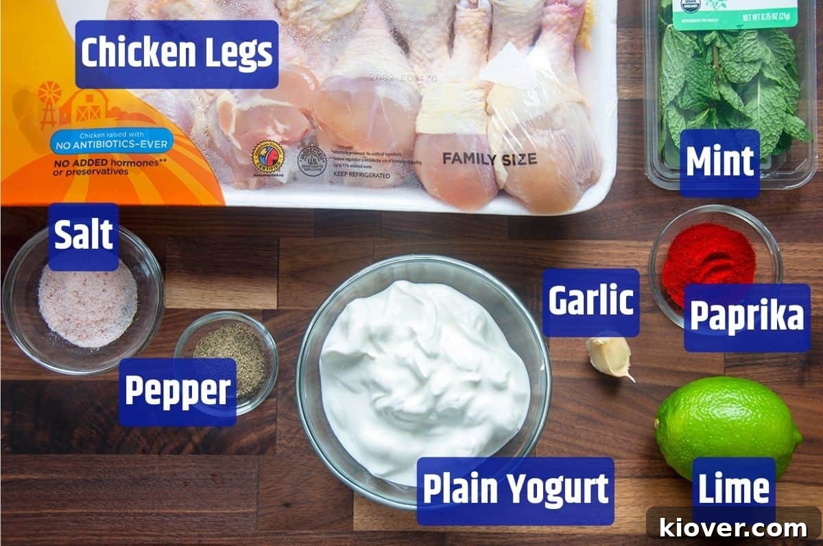 A vibrant display of fresh ingredients for Grilled Chicken Legs with Yogurt Mint Marinade, including chicken legs, mint, paprika, garlic, lime, plain yogurt, pepper, and salt.
