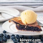 A delectable slice of homemade blueberry pie, perfectly golden and bursting with rich blueberry filling, served on a pristine white plate alongside a scoop of creamy vanilla ice cream, inviting a delightful dessert experience.