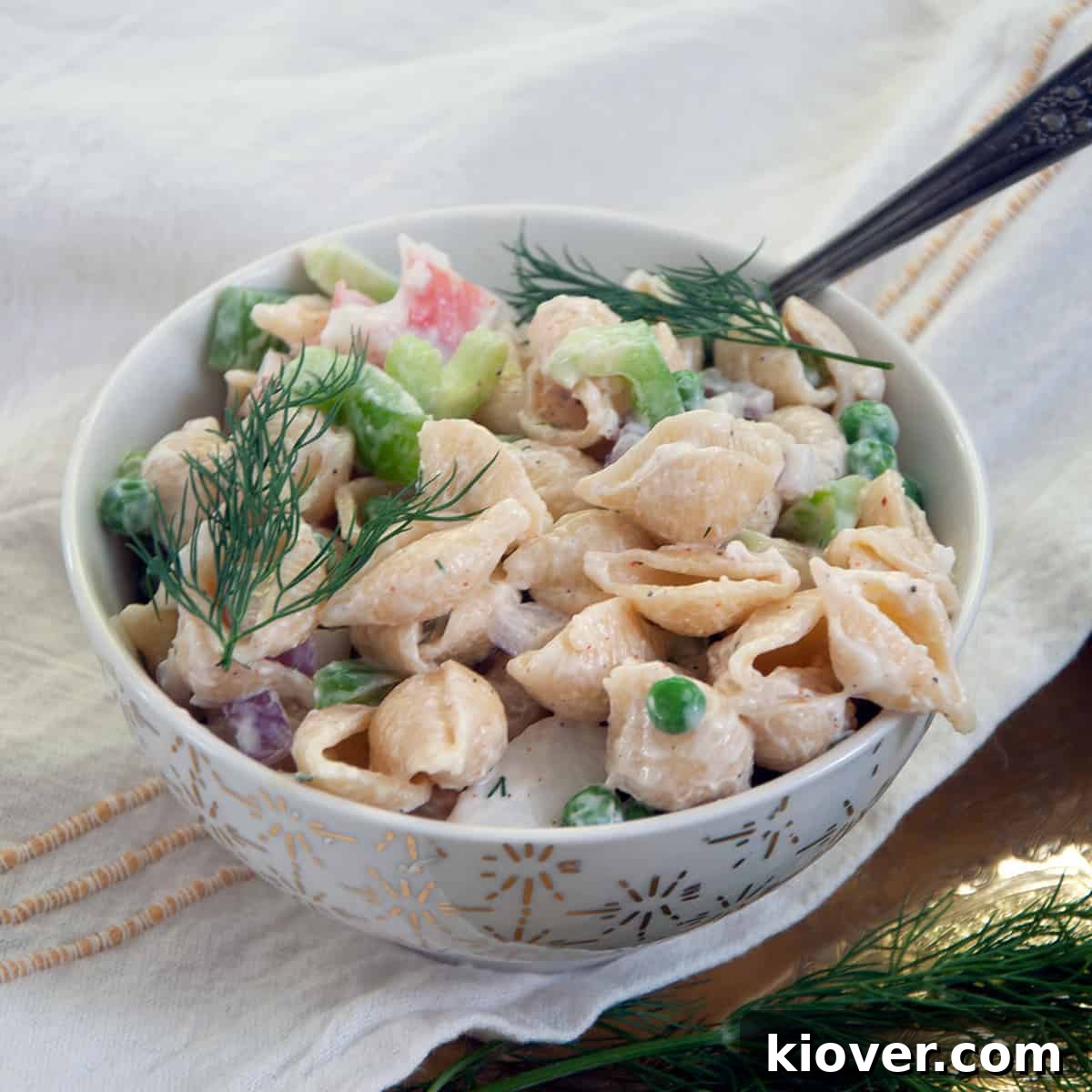 Crab Pasta Salad Crab pasta salad garnished with dill in a white bowl.