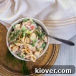 Crab pasta salad in a white bowl on a gold platter.