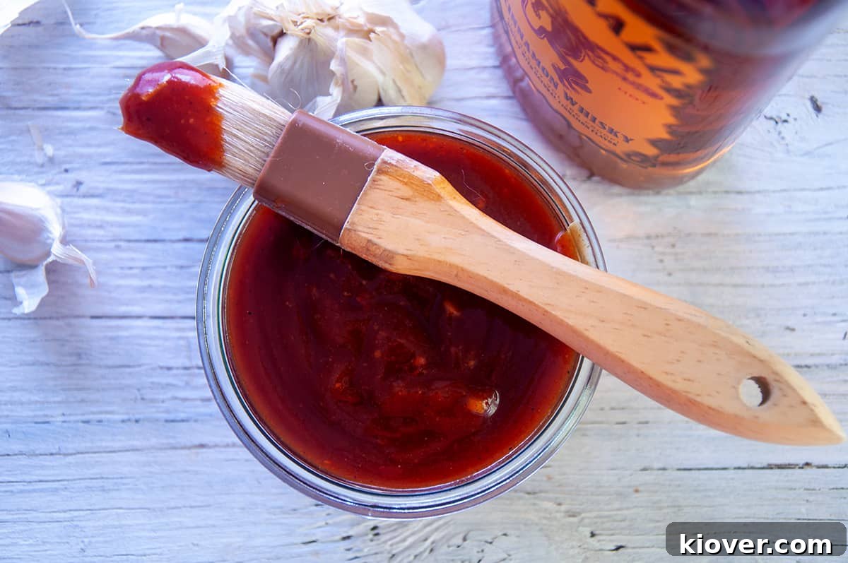 Spicy Fireball Whisky BBQ sauce in a glass dish with a brush on top, ready for application.