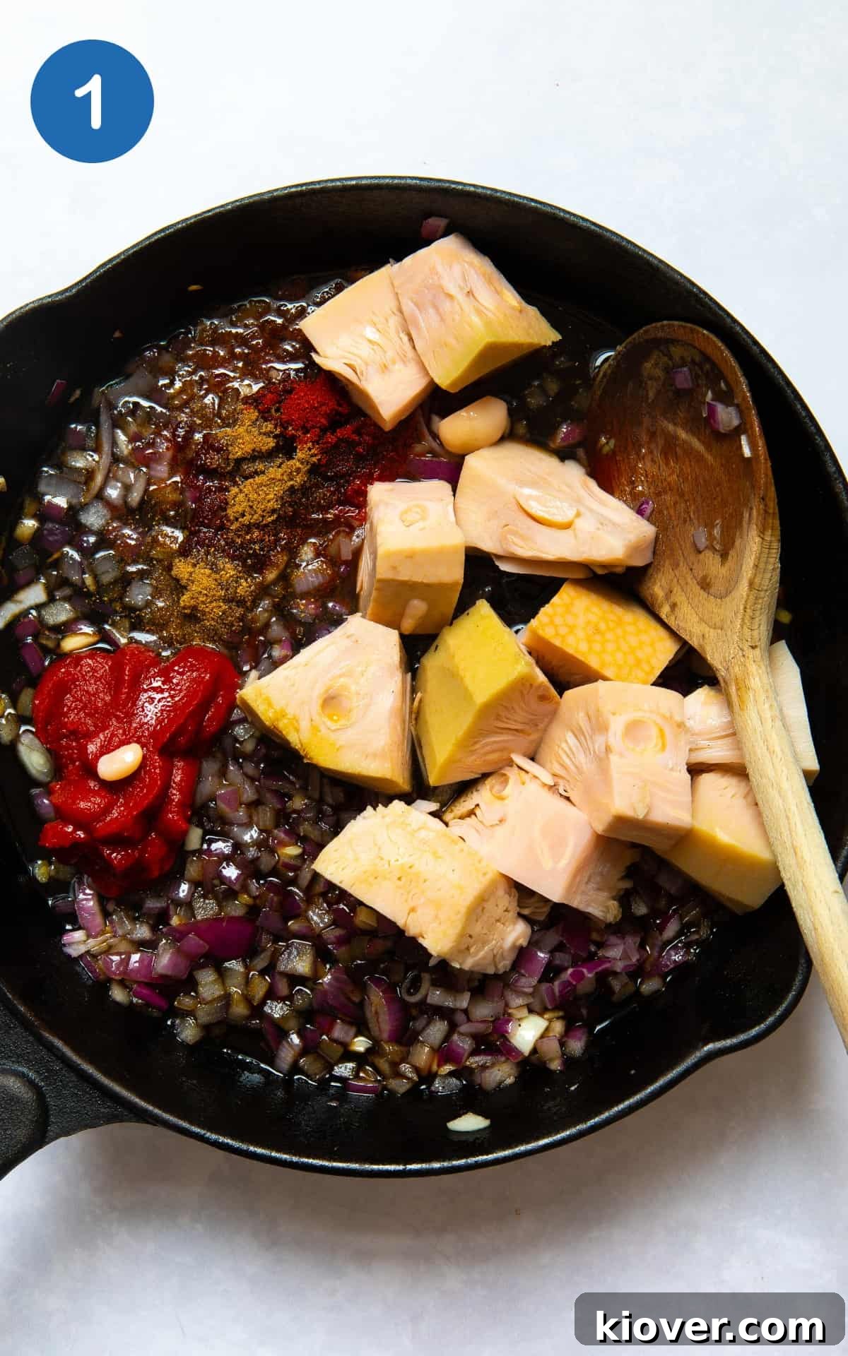 Red onion, garlic, and jackfruit in a pan, ready to be cooked.