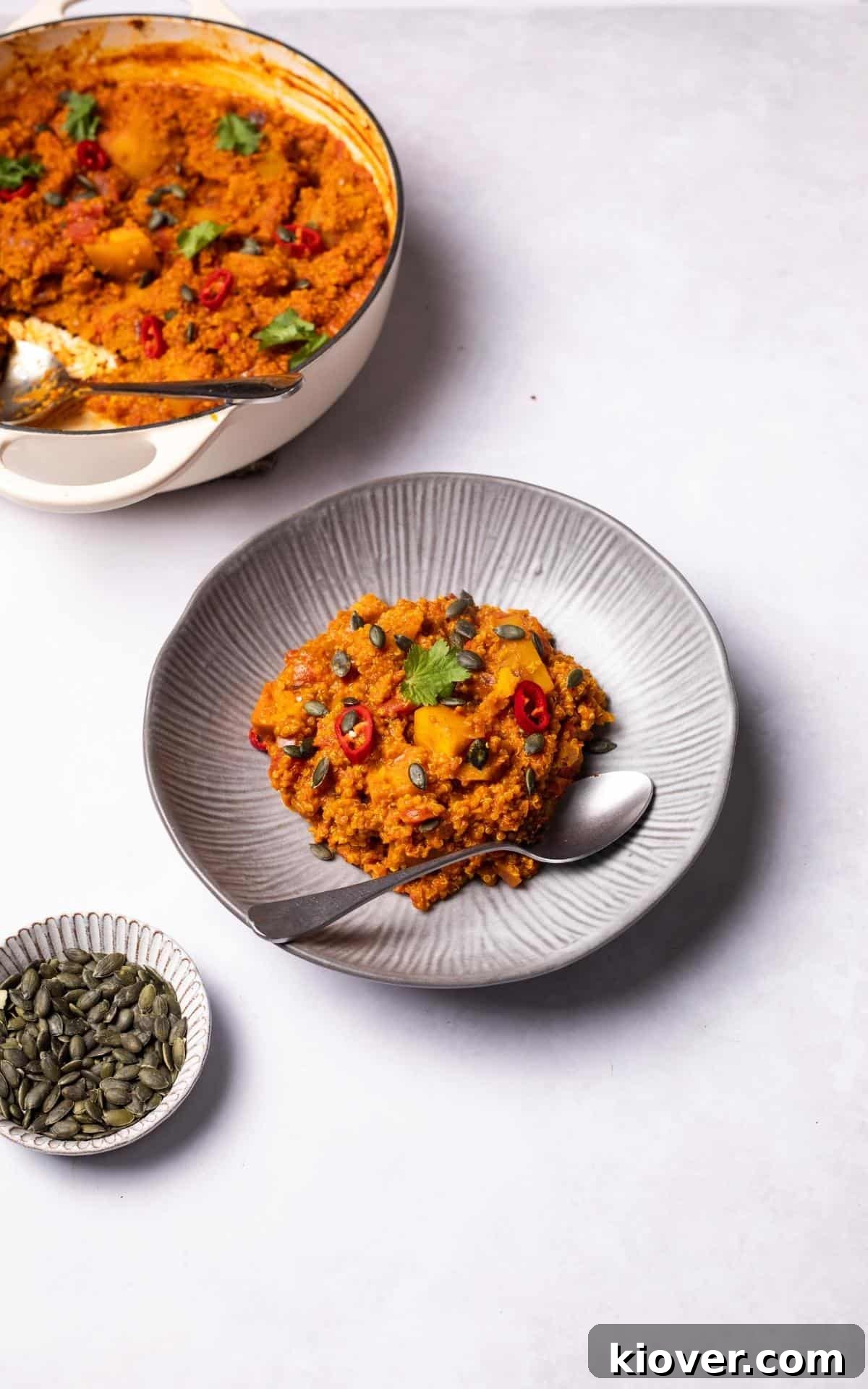 A serving of Pumpkin Curry with Quinoa, garnished with fresh herbs, on a gray plate.