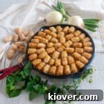 Cast iron tater tot hotdish on a wood table with some oregano.