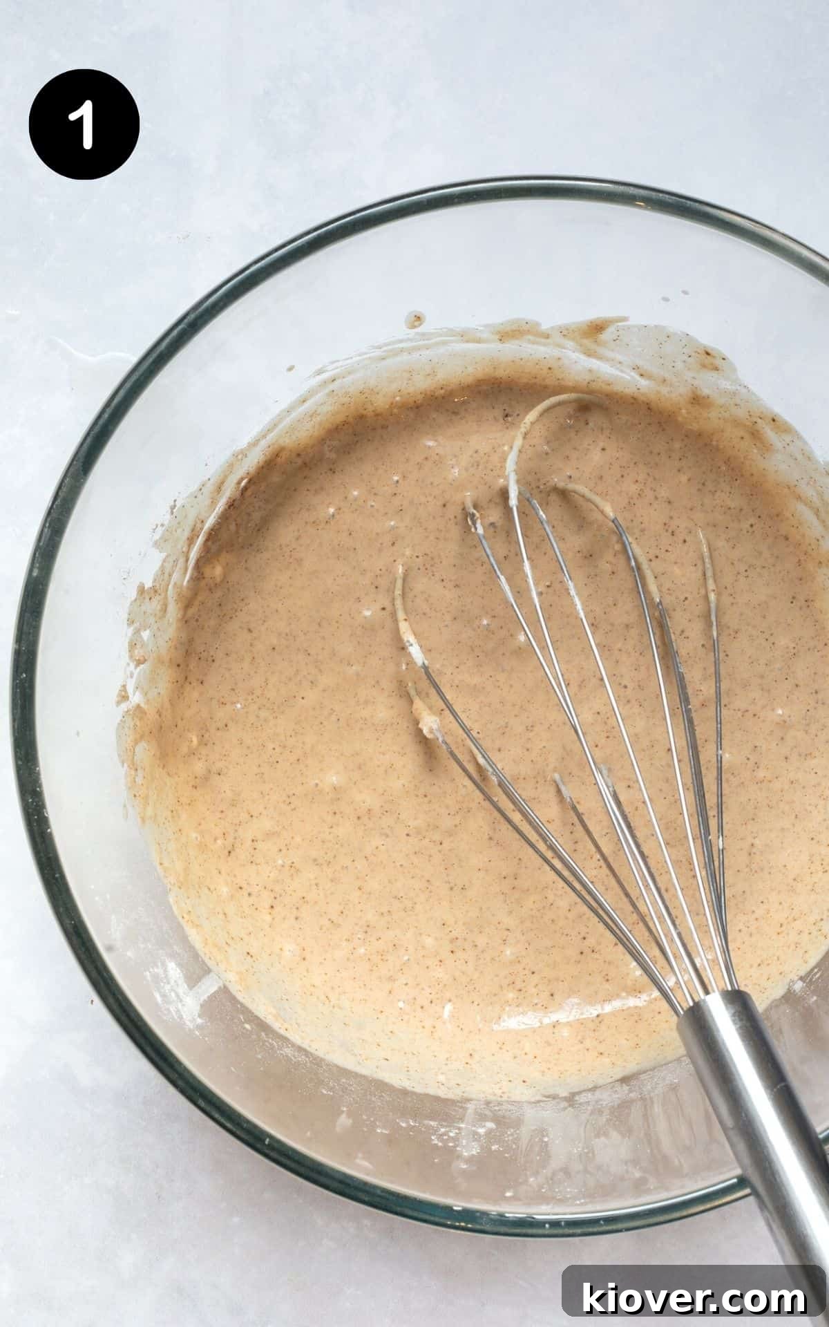 Heavenly Gluten-Free Cinnamon Baked Doughnuts 4 Doughnut batter in a glass mixing bowl with a whisk, showing a smooth, well-combined consistency.