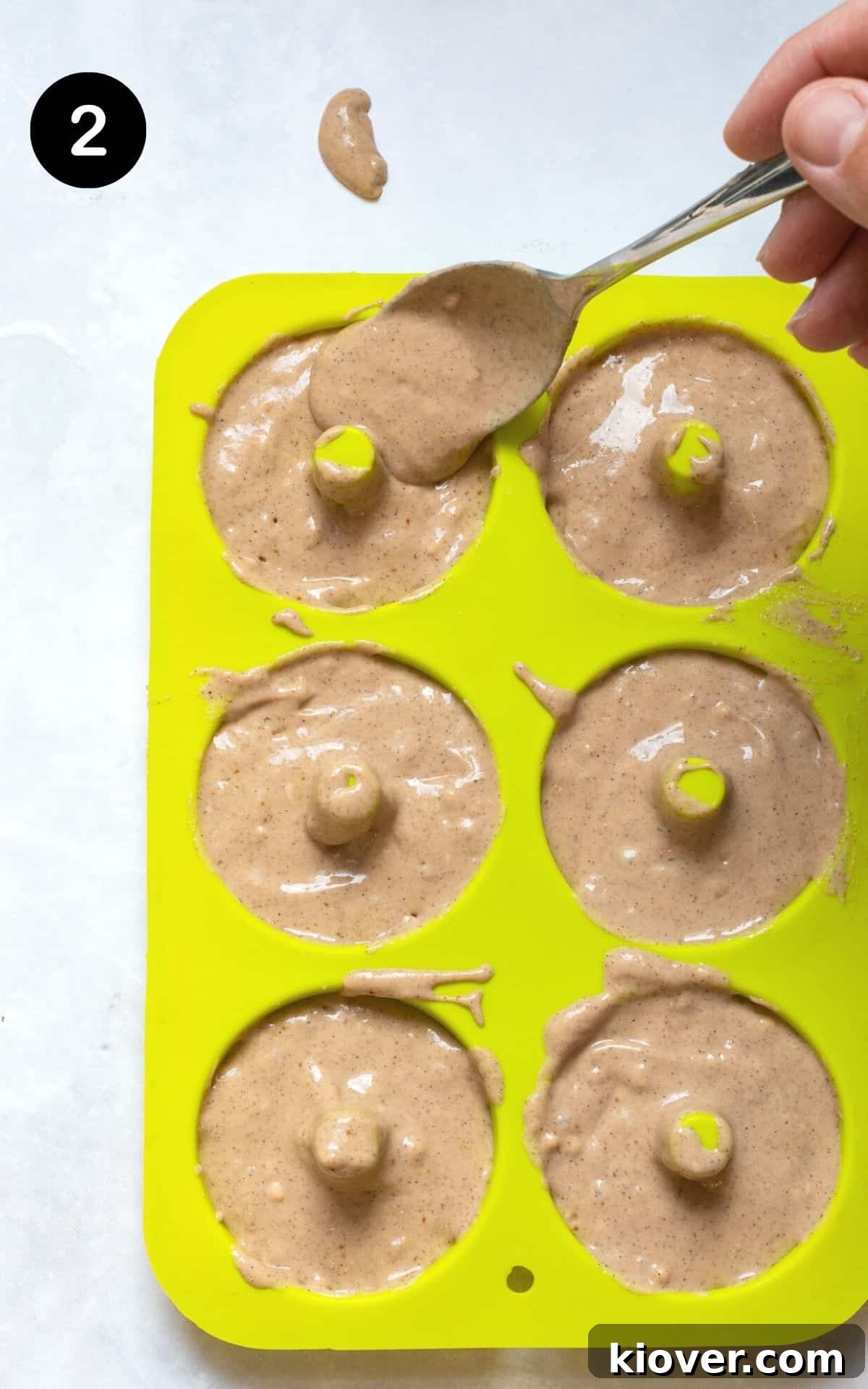 Heavenly Gluten-Free Cinnamon Baked Doughnuts 5 Doughnut batter carefully poured into a green silicone doughnut mould, ready for baking.