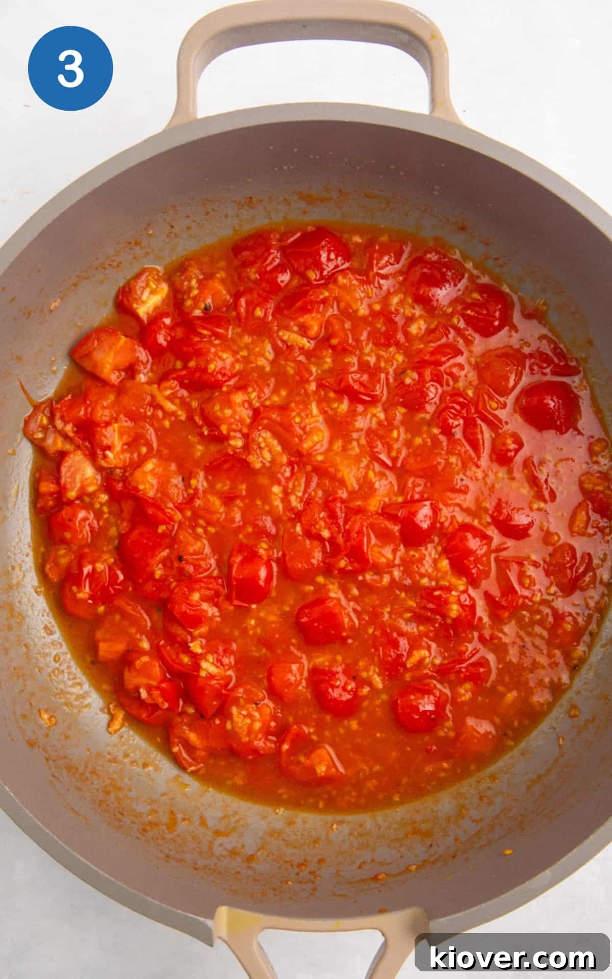 Garlic and quartered cherry tomatoes sautéing in olive oil in a large pan, seasoned with salt and pepper.