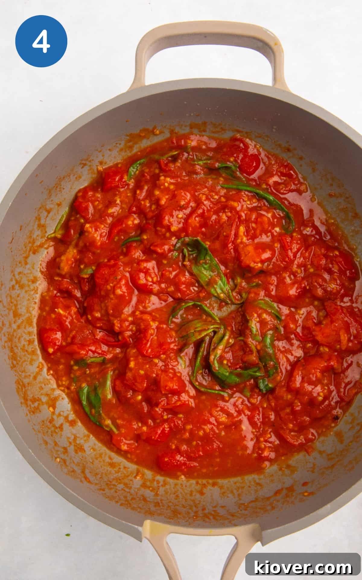 Spices, tomato puree, and miso paste added to the pan with cherry tomatoes, followed by fresh basil leaves.