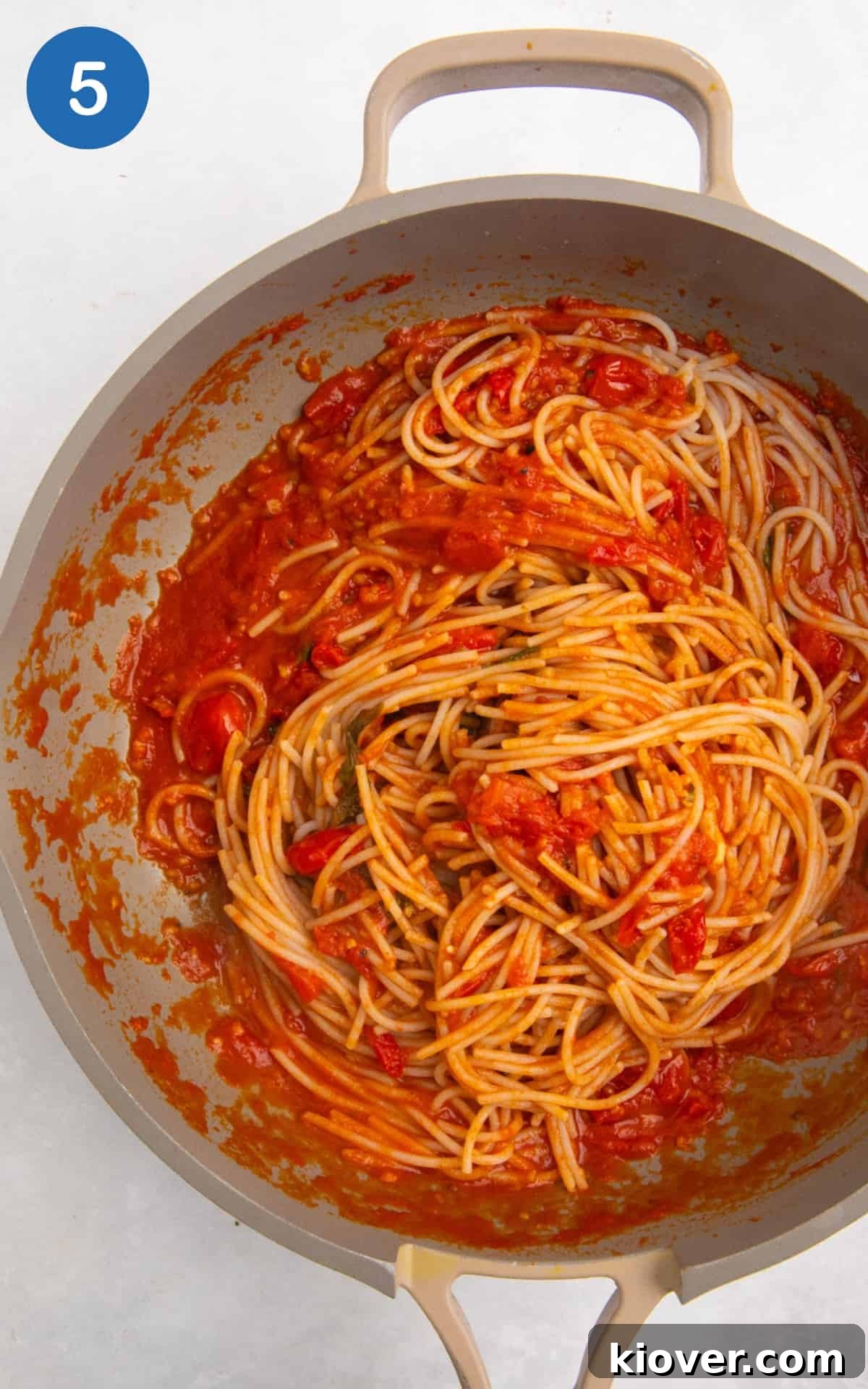 Cooked pasta tossed with the cherry tomato sauce in a large pan, ready to serve.