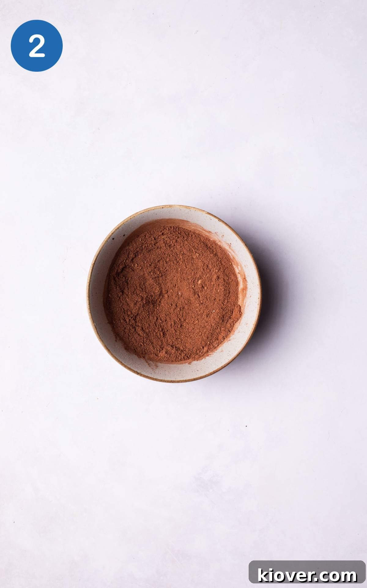 Dry ingredients including oat flour, cacao powder, baking powder, and salt mixed thoroughly in a bowl using a whisk.