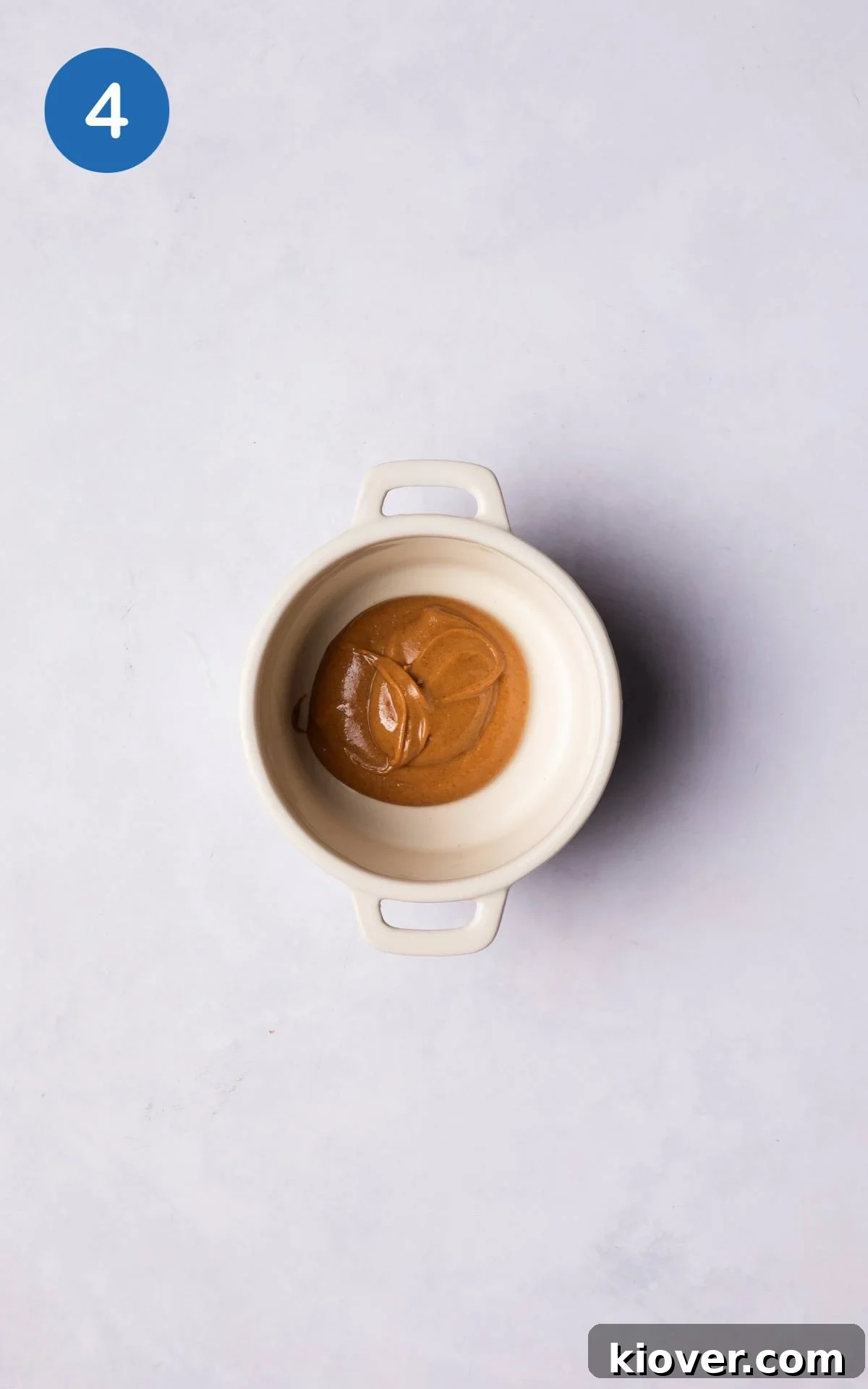 A spoonful of peanut butter placed at the bottom of a ceramic ramekin, ready for the chocolate batter.
