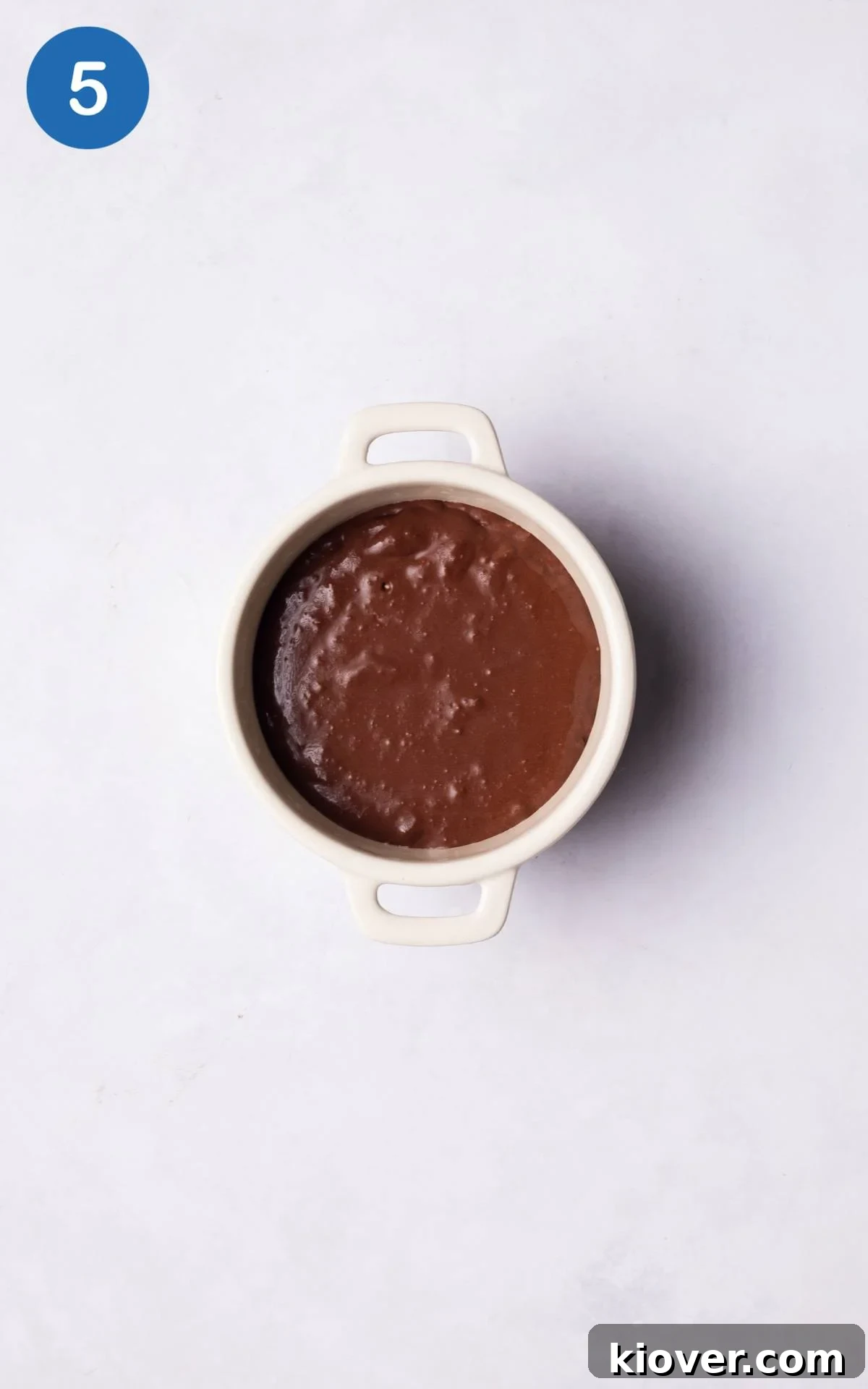 A baked gluten-free chocolate lava cake in a ramekin, showing its firm top and gooey potential.