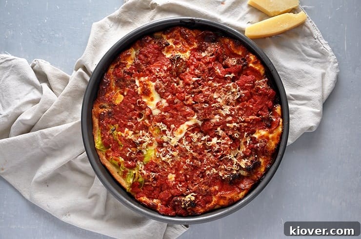 Chicago Style Pizza A Chicago Style Pizza in a pan and on a white kitchen towel. Some parmesan cheese is sitting on the side