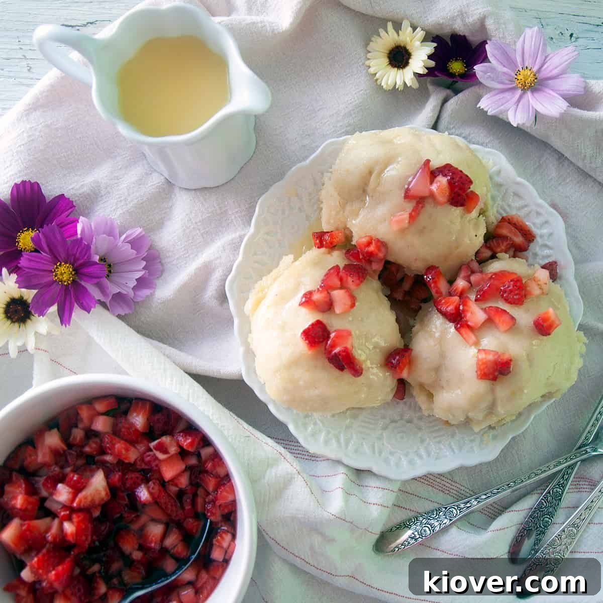 German Dampfnudel Sweet Dumplings Three golden-brown Dampfnudel sweet dumplings adorned with fresh strawberries and a drizzle of vanilla sauce.