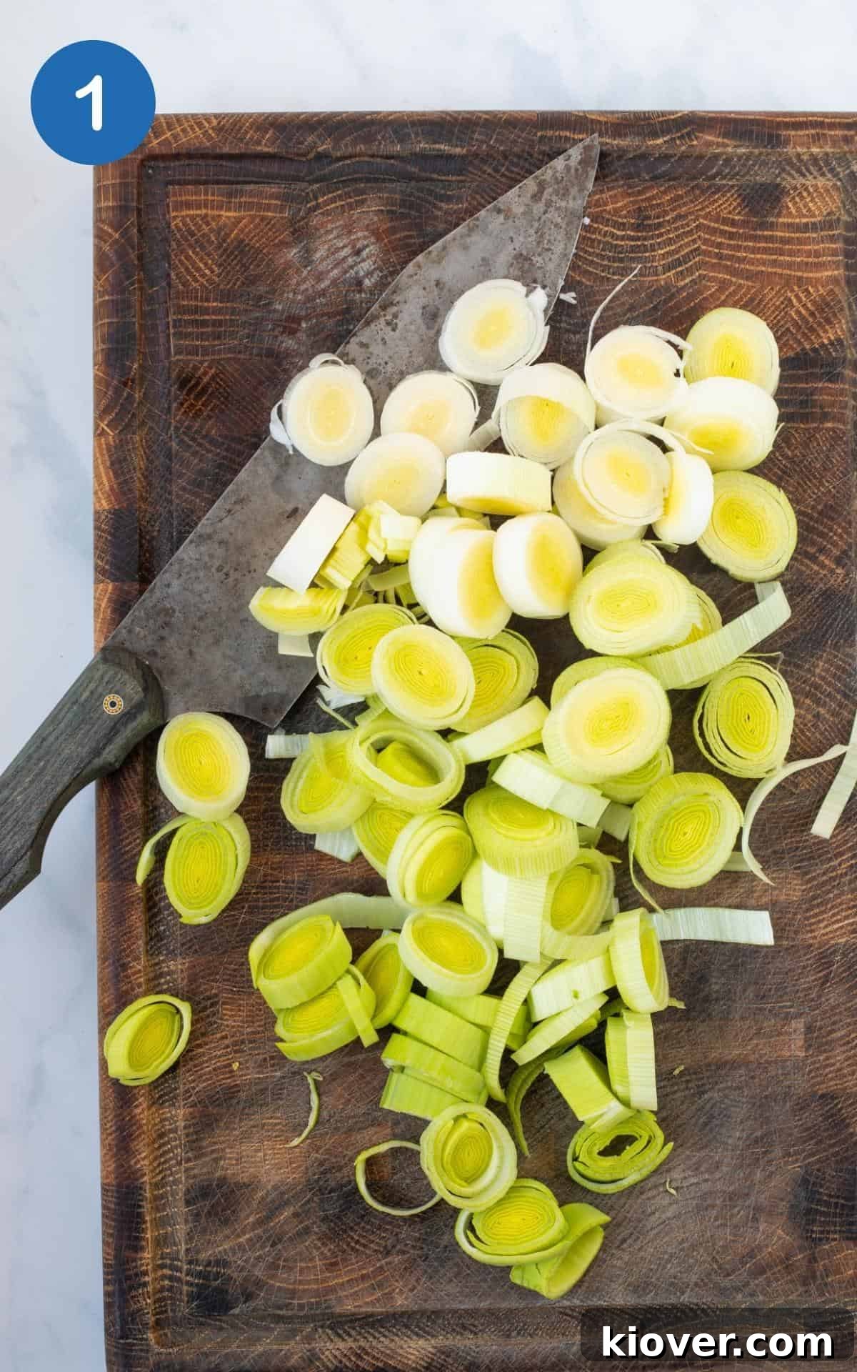 Freshly chopped leeks arranged on a rustic wooden cutting board, ready for cooking.