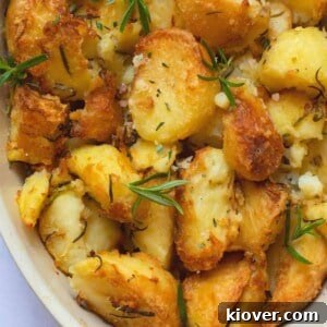 rosemary infused roast potatoes in a baking dish on a white marble background