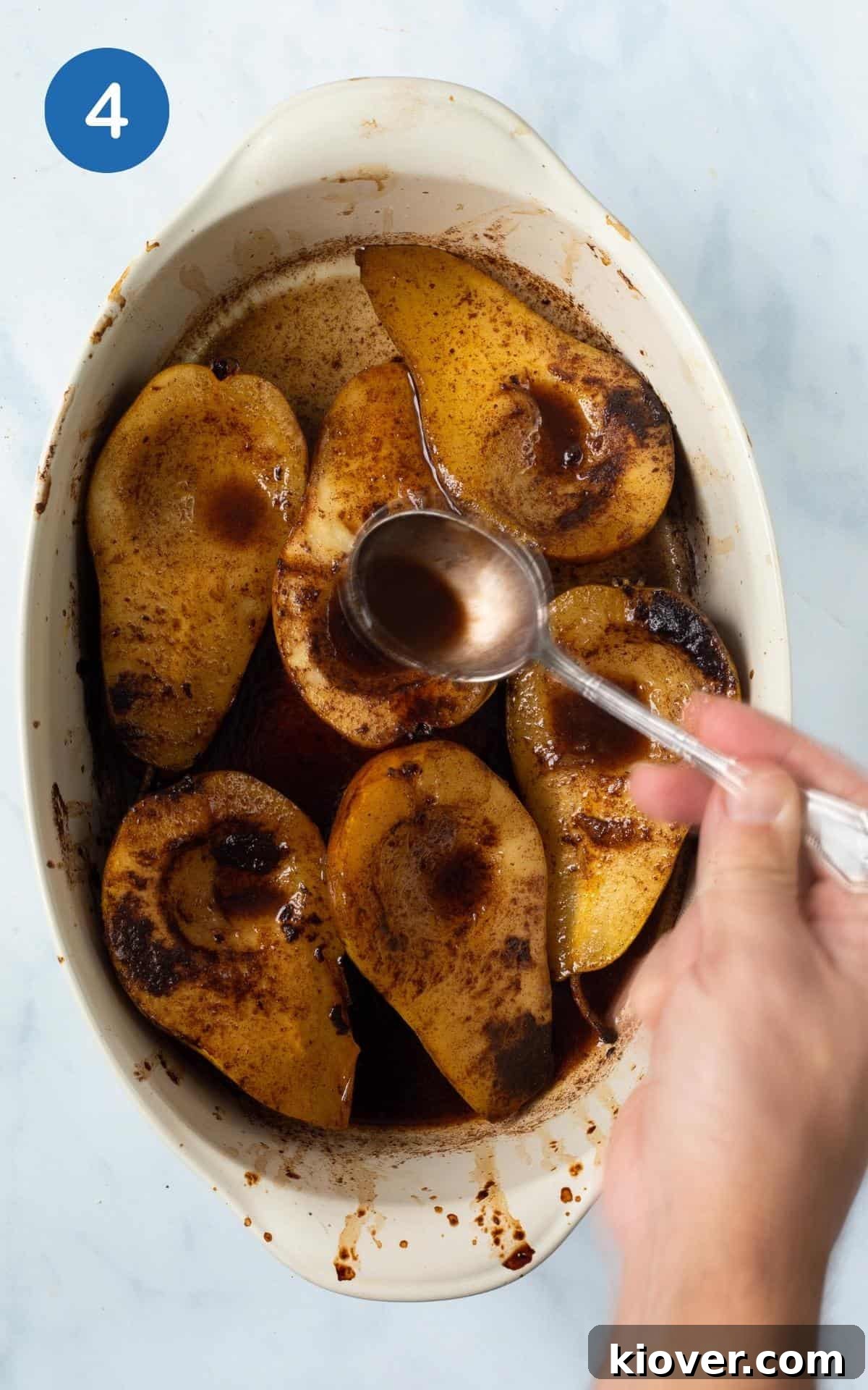 baked spiced pears basted with sauce with silver spoon.