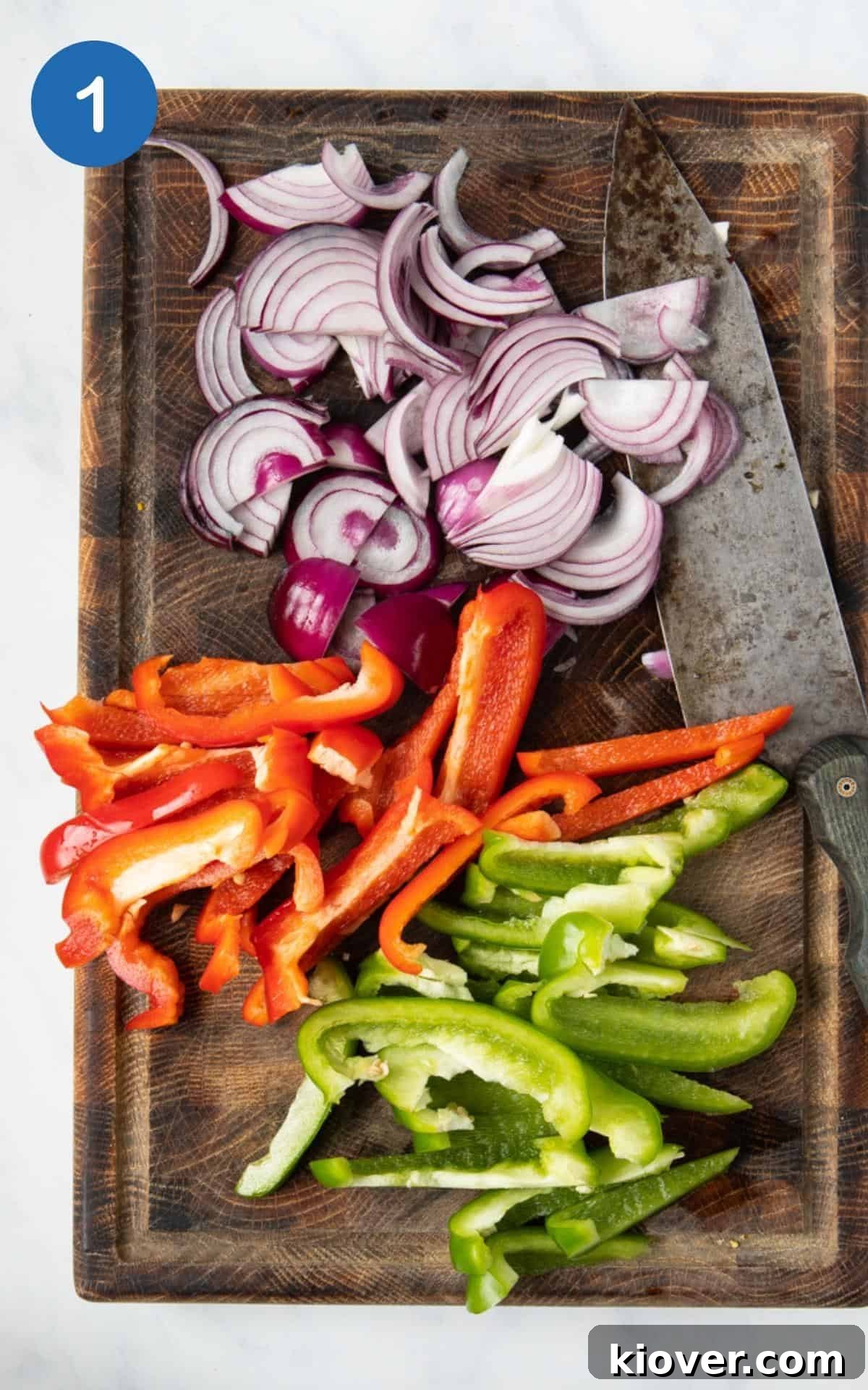 Chopped red onions, red pepper and green pepper on a chopping board, ready for mixing.