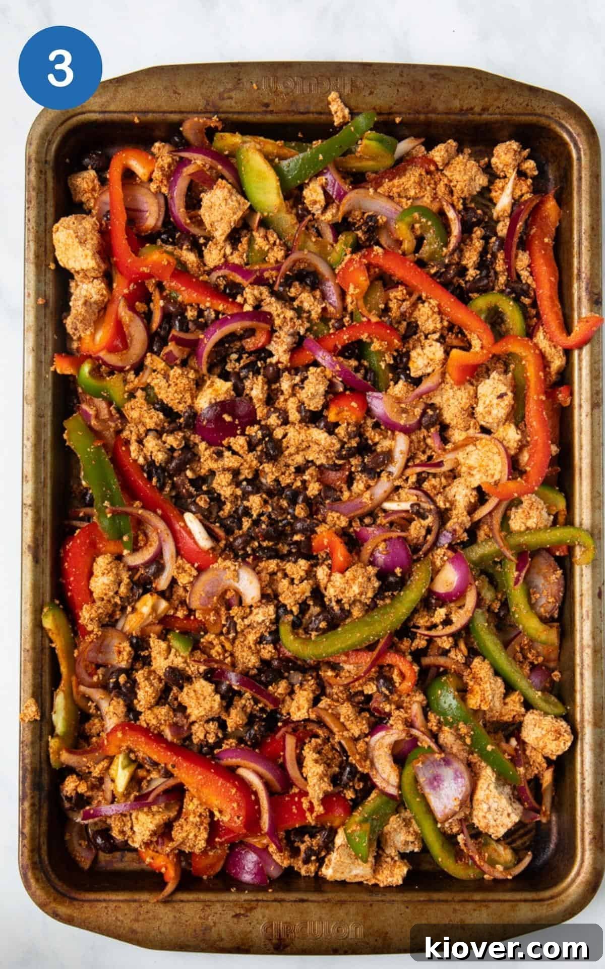 Spiced Tofu, Black Beans, Red Pepper, Tamari, Olive oil, red onion, and green pepper spread evenly in a baking pan for homemade tofu fajitas.