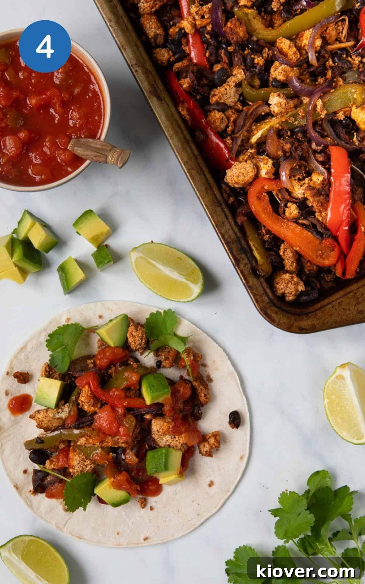 Baked Sheet Pan Tofu Fajitas in a baking pan, with a prepared gluten-free tortilla topped with salsa, cilantro, and avocados off to the side, ready to be served.